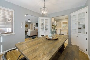 A dining area with a wooden table, white cabinets, and a chandelier. - Downtown home w/private hot tub, pool table, gas grill, W/D, AC (Paso Robles)