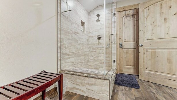 A shower with glass doors, a wooden bench, and a wooden door. - Charming Townhouse with WiFi, Wood-Burning Fireplace, and Private Washer/Dryer (Breckenridge)