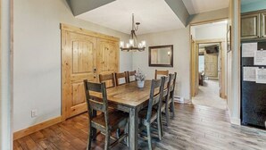 A dining area with a wooden table and chairs, a chandelier, and wooden cabinets. - Charming Townhouse with WiFi, Wood-Burning Fireplace, and Private Washer/Dryer (Breckenridge)