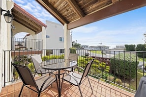 A covered balcony with a round table and chairs, a pergola, and a view of a residential area. - Classic getaway by the sea within walking distance to everything w/ocean views (Cayucos)