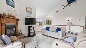A living room with a fireplace, a television, a sofa, and a dining area. - Classic getaway by the sea within walking distance to everything w/ocean views (Cayucos)