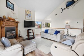 A living room with a fireplace, a television, a sofa, and a dining area. - Classic getaway by the sea within walking distance to everything w/ocean views (Cayucos)