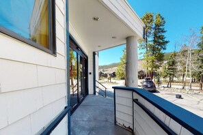 A building exterior with a covered entrance, a concrete pathway, and a parking area with a car. - Condo in the Heart of River Run Village, with Jet Tub & Mountain Views (Keystone)