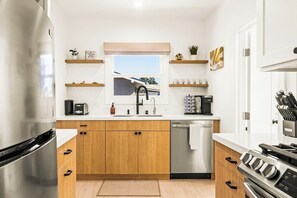 Eine moderne Küche mit Holzschränken, einem Edelstahlkühlschrank, einer Spülmaschine und einem Herd.