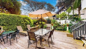 An outdoor patio with a table and chairs, surrounded by greenery and a staircase.