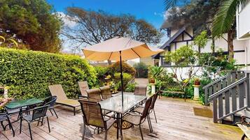 An outdoor patio with a table and chairs, surrounded by greenery and a staircase.