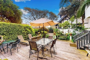 Eine Terrassesituation mit Tisch und Stühlen, umgeben von Grünpflanzen und einer Treppe.