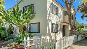 A two-story building with a white exterior, multiple windows, and a white picket fence.