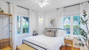 A bedroom with a bed, bedside tables, a bench, and a window with curtains.