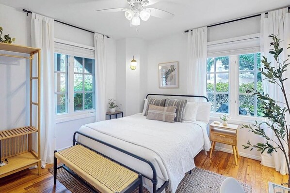 A bedroom with a bed, bedside tables, a bench, and a window with curtains.