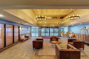 A spacious lobby with a high ceiling, large windows, and a view of the sea. There are multiple seating areas with sofas and chairs. - Cozy Condo with Stunning Mountain Views, Hot Tub, and Fireplace (Crested Butte)