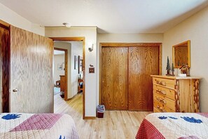 Une chambre avec deux lits, des armoires en bois, une commode et un miroir.
