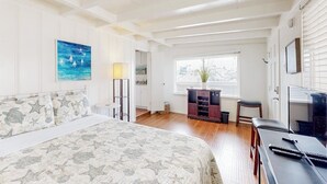 A bedroom with a bed, a desk, a chair, a lamp, a window, and a painting. - Cozy duplex with oceanview balcony - steps to the beach (Ventura)