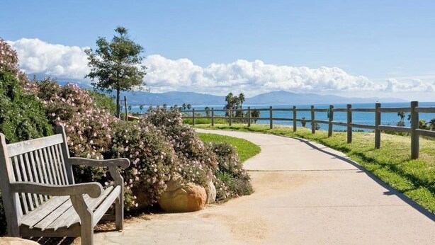 A bench, a pathway, and a view of the sea with mountains in the background. - Cozy duplex with oceanview balcony - steps to the beach (Ventura)