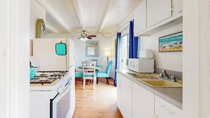A narrow kitchen with white cabinets, a stove, and a microwave. - Cozy duplex with oceanview balcony - steps to the beach (Ventura)