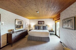 Ein Schlafzimmer mit einem großen Bett, einem Schminktisch, einem Spiegel, Nachttischlampen und einem gerahmten Bild an der Wand.