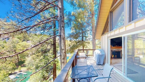 Une terrasse dotée de mobilier d’extérieur, d’un foyer et offrant une vue sur une piscine entourée d’arbres.