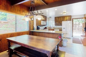 A kitchen with wooden cabinets, a wooden dining table, and pendant lights. - Serene lakefront getaway with game room, fireplace, & washer/dryer (Lake Arrowhead)