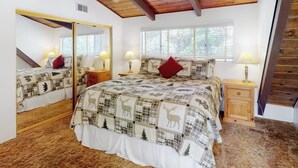 Une chambre avec un grand lit, un miroir, une fenêtre et un plafond en bois.