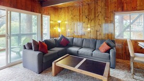 Un salon chaleureux avec un canapé d’angle, une table basse et un plafond en bois.