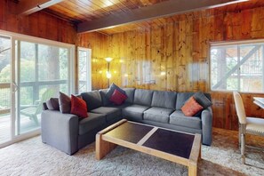 A cozy living room with a sectional sofa, a coffee table, and a wooden ceiling. - Serene lakefront getaway with game room, fireplace, & washer/dryer (Lake Arrowhead)