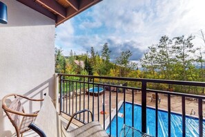 Ein Balkon mit Pool, Gartenmöbeln und Blick auf Bäume und Hügel.
