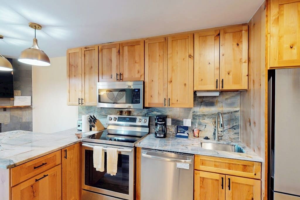 A kitchen with wooden cabinets, stainless steel appliances, and a marble countertop.