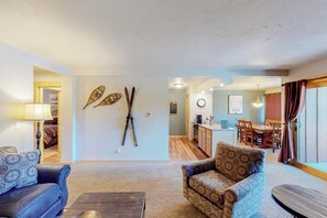 A living room with a sofa, armchair, and coffee table. There is a kitchen area visible in the background. - Mountain view condo with hot tub, walk to Snowflake Lift & Main Street (Breckenridge)