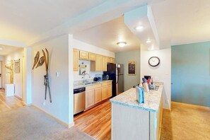 A modern kitchen with wooden cabinets, a built-in oven, and a granite countertop. - Mountain view condo with hot tub, walk to Snowflake Lift & Main Street (Breckenridge)