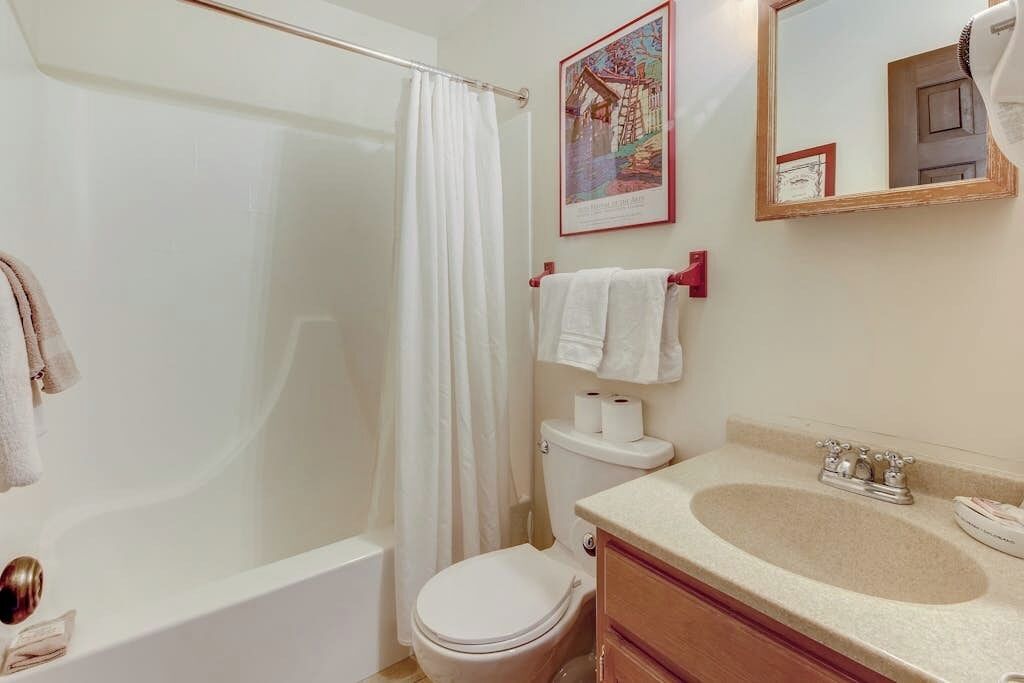 A bathroom with a bathtub, toilet, sink, and a shower curtain.