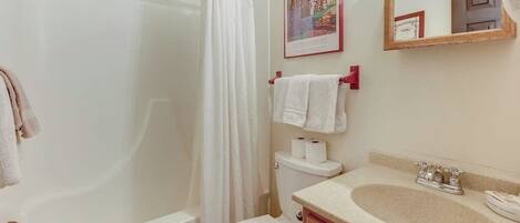 A bathroom with a bathtub, toilet, sink, and a shower curtain.