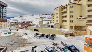 Et hotel med flere etager, en parkeringsplads og udsigt til et snedækket bjerg.
