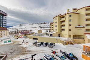 Ein Hotel mit mehreren Stockwerken, einem Parkplatz und Blick auf einen verschneiten Berg.