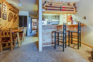 Ein rustikales Interieur mit Holzwänden, einem Essbereich mit Holzsesseln und einer Küche mit Holzschränken.