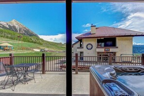 A view of a mountain, a building with a sign 'CAMP', and a hot tub. - Ski-in/out condo at the base of Silver Queen lift with seasonal hot tub (Crested Butte)
