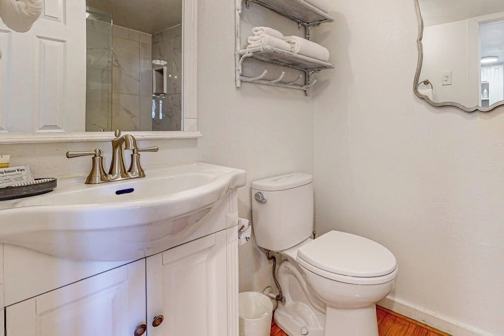 Een badkamer met een wit wastafel, toilet, spiegel en douche.
