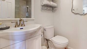 Een badkamer met een wit wastafel, toilet, spiegel en douche.