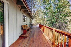 Eine Holzterrasse mit einer Bank und einem Mülleimer.