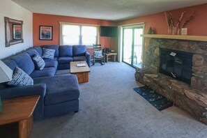 Ein Wohnzimmer mit einem blauen Sofa, einem Kamin und einem Fernseher.