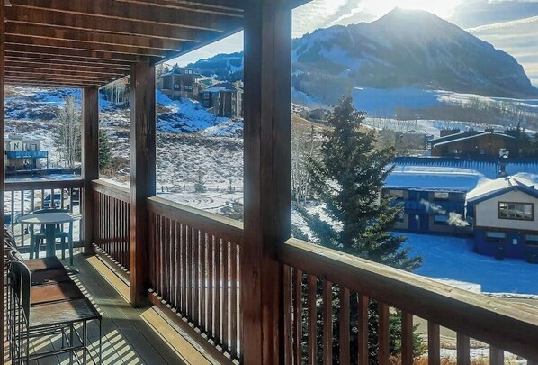 Ein hölzerner Balkon mit Blick auf eine verschneite Berglandschaft und Gebäude.