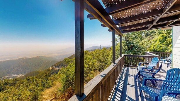 Eine Holzterrasse mit Stühlen mit Blick auf eine gebirgige Landschaft.