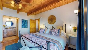 Ein Schlafzimmer mit einem Bett, einem Schminktisch, einem Spiegel und einem Deckenventilator.