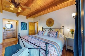 Ein Schlafzimmer mit einem Bett, einem Schminktisch, einem Spiegel und einem Deckenventilator.