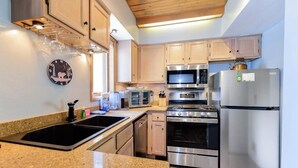 Une cuisine moderne dotée de plans de travail en granit, d’appareils électroménagers en acier inoxydable et d’armoires en bois.