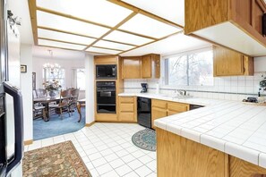A modern kitchen with wooden cabinets, a built-in oven, and a large window. - Multi-level home with pool table, AC, fireplaces, balcony & gorgeous views (Lake Arrowhead)