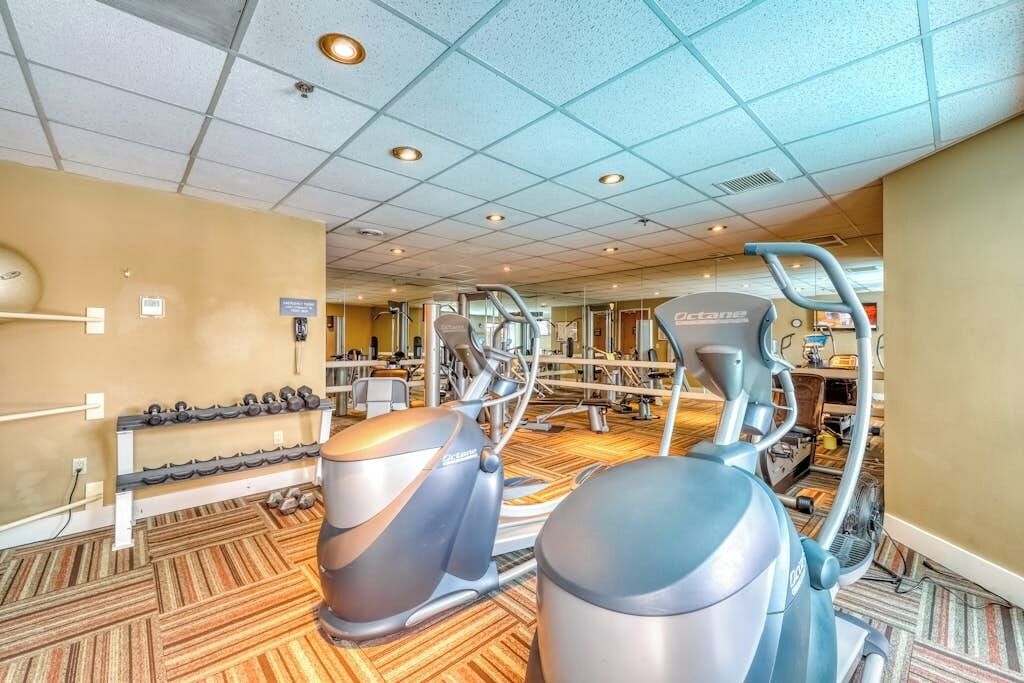 Een sportschool met fitnessapparatuur, een rek voor gewichten en een spiegel.