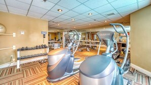 Un gimnasio con equipo de ejercicio, un soporte para pesas y un espejo.