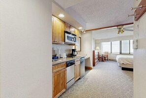 A compact kitchen with wooden cabinets, a microwave, and a dishwasher. - Efficient Mountain Escape W/ Murphy Bed, Shared Pool, Slope Access & Kitchenette (Crested Butte)