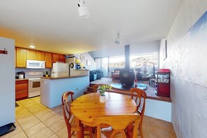 Eine Küche mit Holzschränken, einer Mikrowelle und einem Herd. Es gibt einen Essbereich mit einem Holztisch und Stühlen.