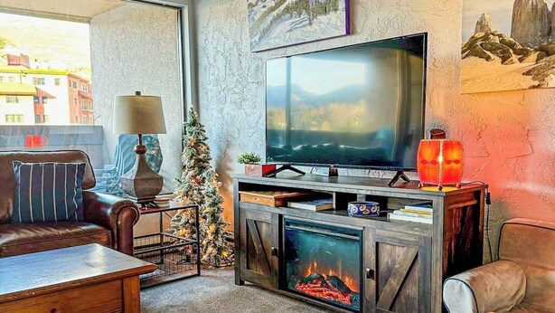 Una sala de estar acogedora con chimenea, televisor y un árbol de Navidad.